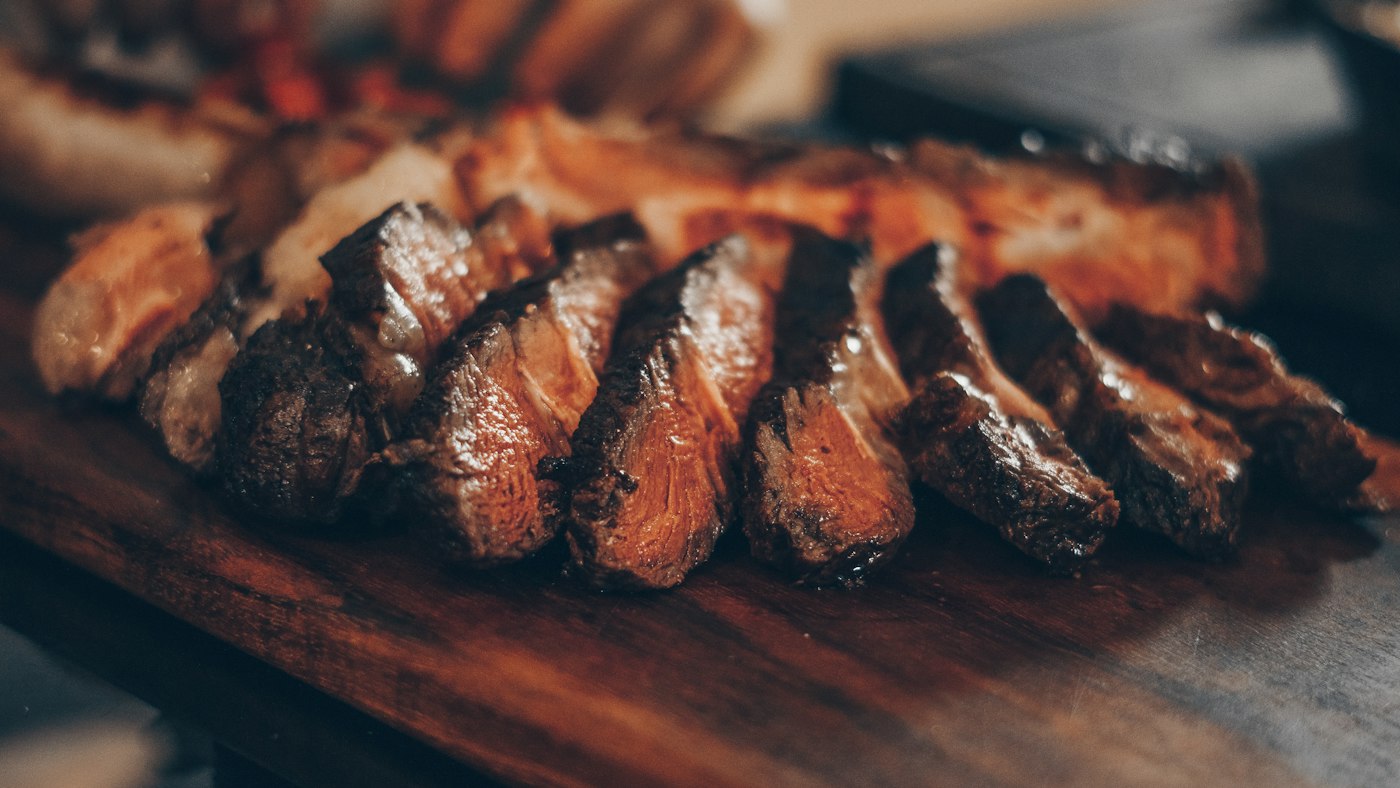 Sliced grilled steak with rosemary on a wooden board