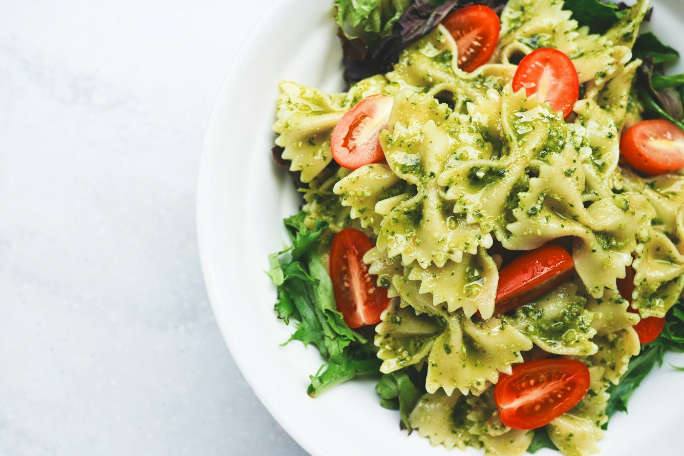 A bowl of pasta with basil and tomatoes