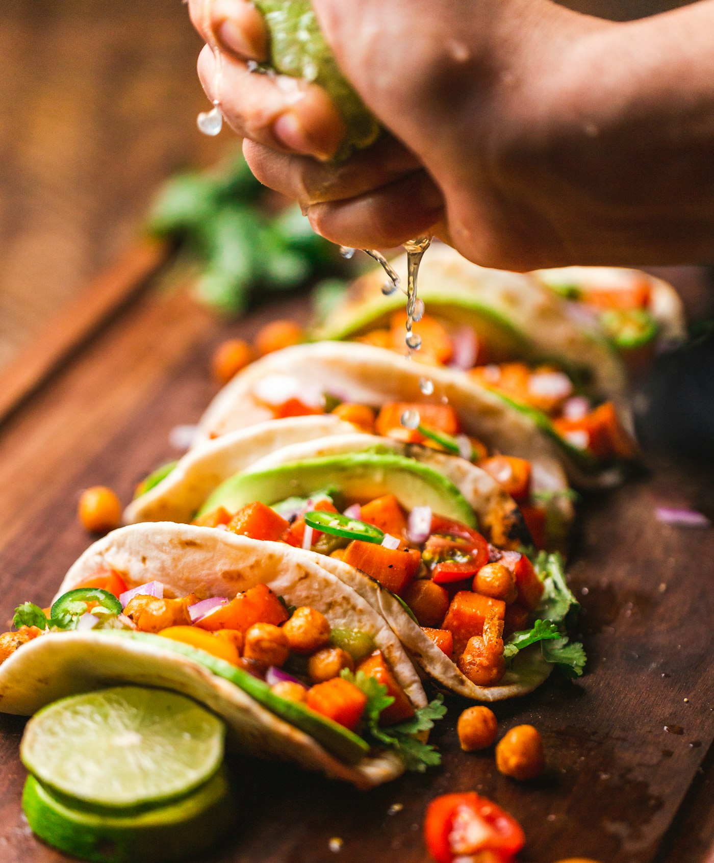 Tacos on a wooden board as lime is squeezed over them